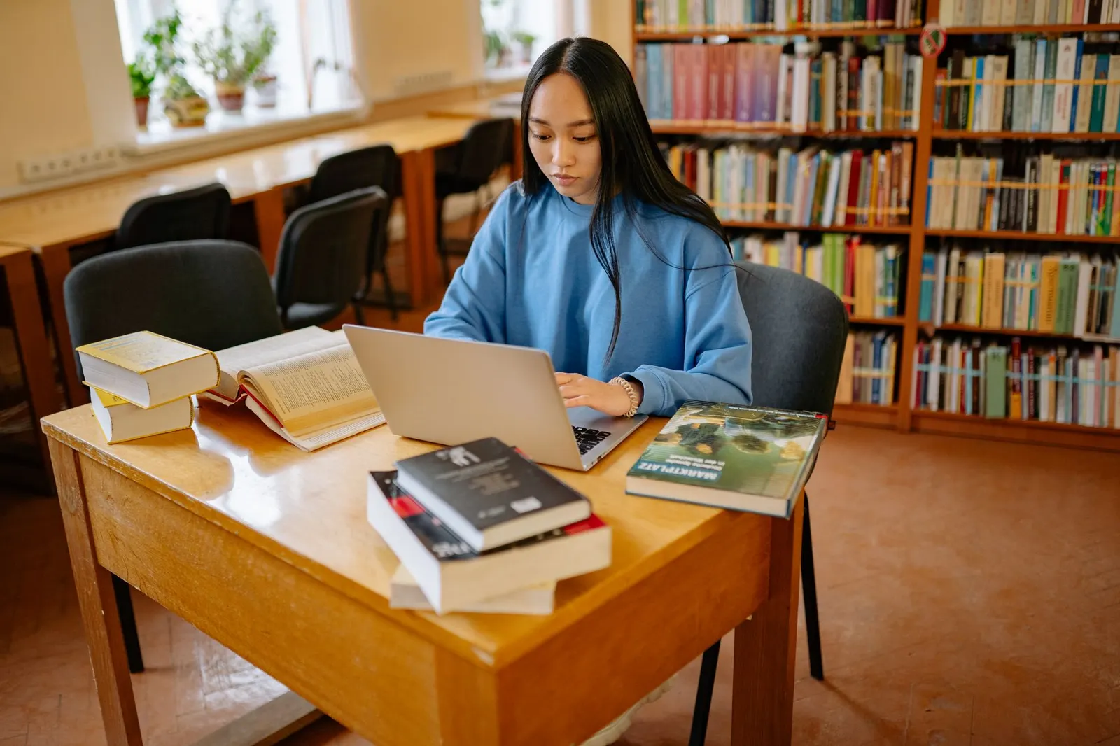 學員在圖書館長桌前使用筆電與書本學習