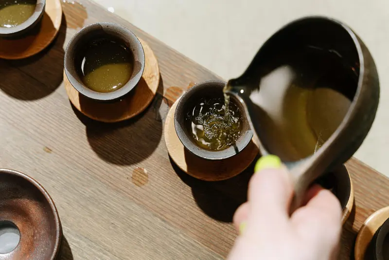木桌上的兩只茶杯，正在注入茶湯