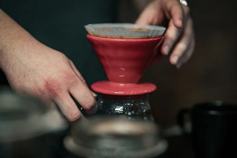 手扶著紅色濾杯在手沖咖啡