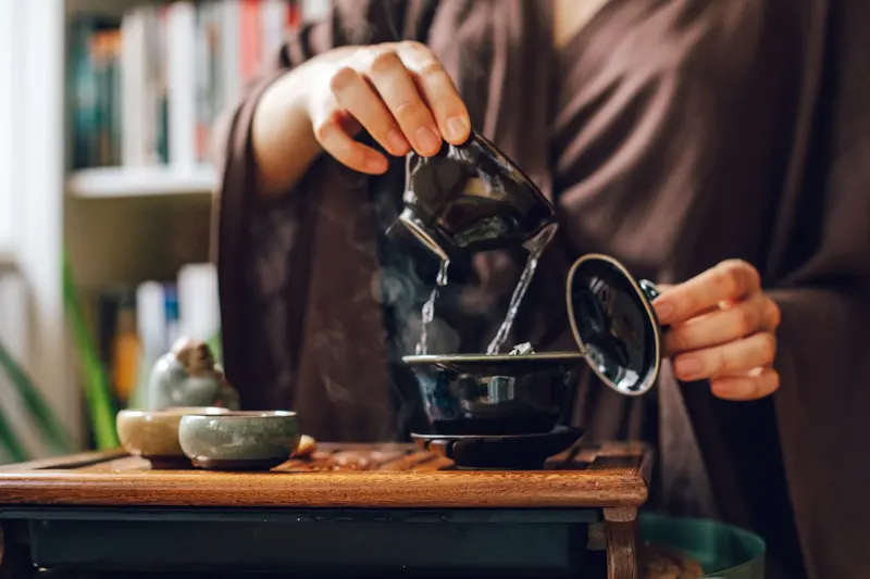 深色木桌上的泡茶器具與側把壺